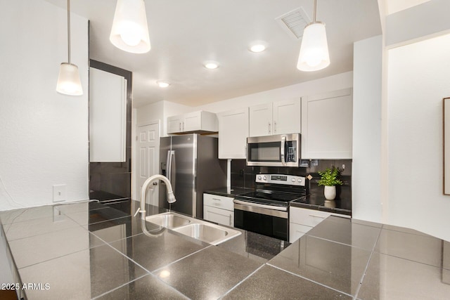 kitchen with appliances with stainless steel finishes, a sink, tasteful backsplash, white cabinetry, and recessed lighting