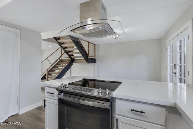 kitchen with white cabinetry, stainless steel electric range oven, light hardwood / wood-style floors, and island range hood