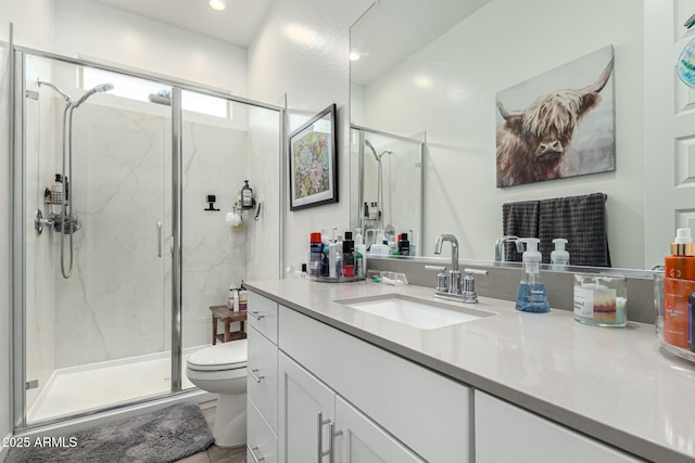 bathroom featuring vanity, toilet, and a shower with shower door