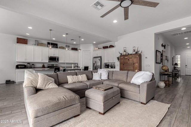 living room with ceiling fan and light wood-type flooring