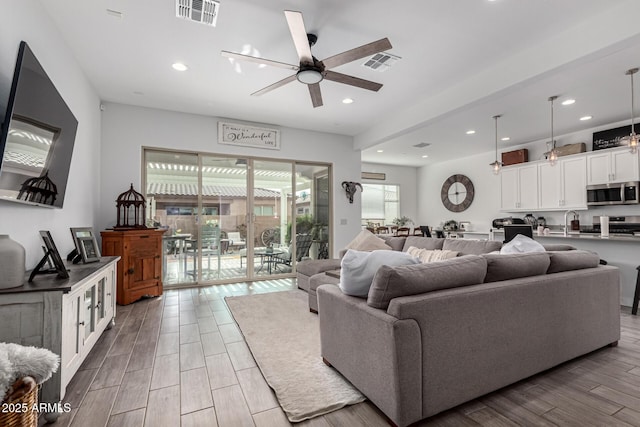 living room featuring sink, light hardwood / wood-style flooring, and ceiling fan