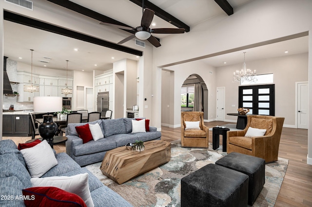 living room featuring a chandelier, arched walkways, light wood-type flooring, beamed ceiling, and recessed lighting
