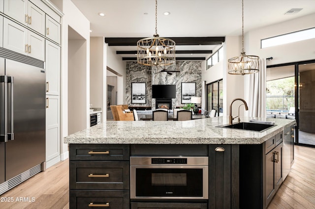 kitchen with a chandelier, appliances with stainless steel finishes, a sink, light wood-style flooring, and recessed lighting