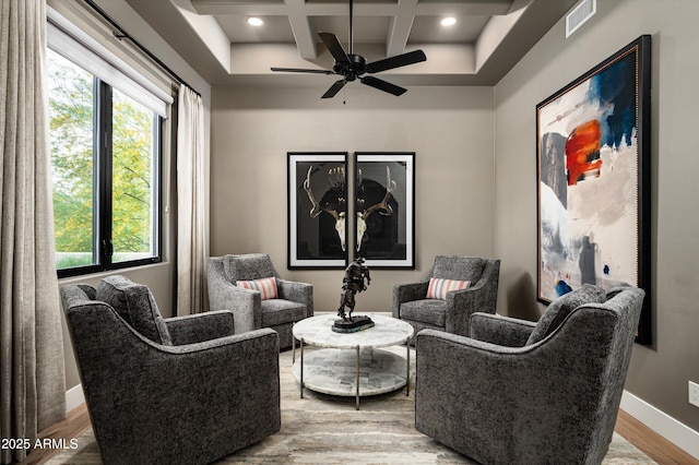 living area featuring coffered ceiling, wood finished floors, healthy amount of natural light, baseboards, and beam ceiling