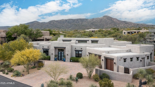 pueblo revival-style home with french doors, a mountain view, and stucco siding