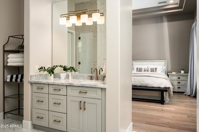 ensuite bathroom with a marble finish shower, vanity, baseboards, and wood finished floors