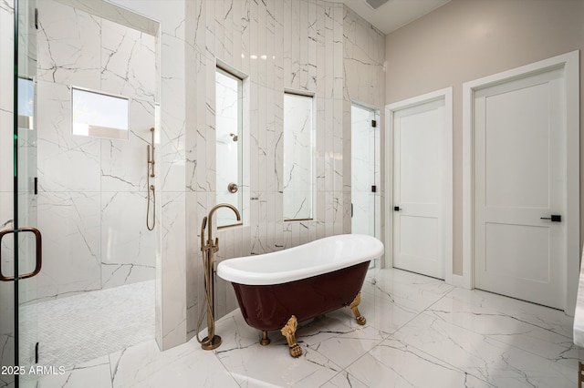 bathroom featuring marble tiled floors, a soaking tub, and a marble finish shower
