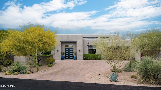 southwest-style home with french doors, stucco siding, and decorative driveway