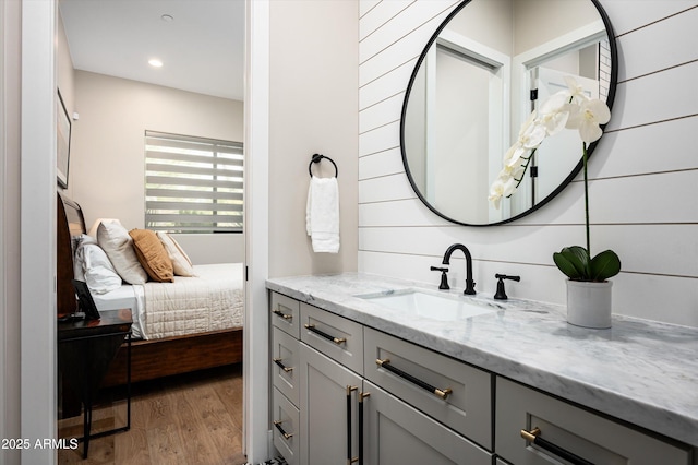 bathroom with wood finished floors, vanity, ensuite bath, and recessed lighting