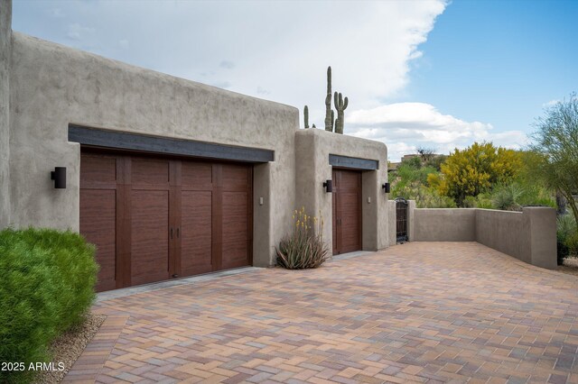 garage with decorative driveway and a gate