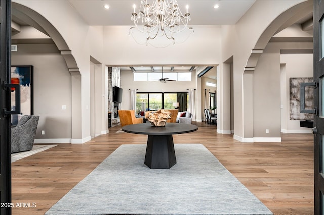 dining area featuring arched walkways, light wood finished floors, a chandelier, baseboards, and recessed lighting