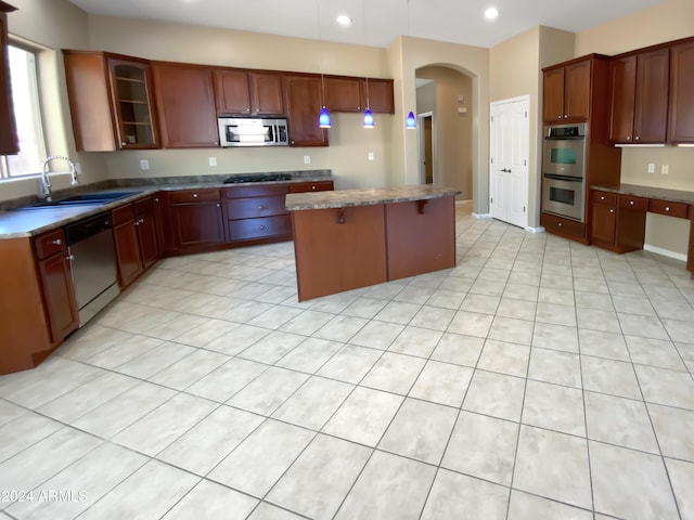 kitchen featuring light tile patterned flooring, stainless steel appliances, a kitchen island, and sink