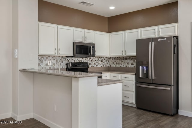 kitchen with kitchen peninsula, backsplash, stainless steel appliances, and white cabinetry