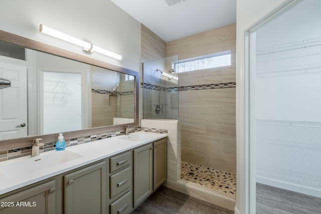 bathroom with vanity, tiled shower, and tasteful backsplash