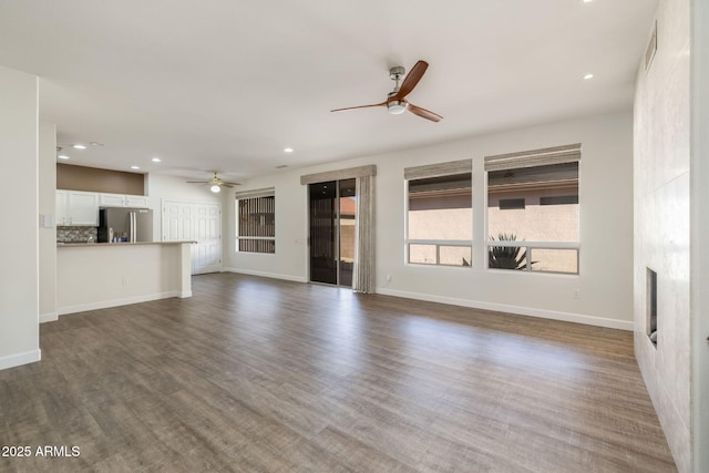 unfurnished living room with ceiling fan, wood-type flooring, and a fireplace