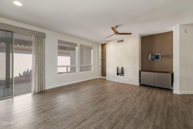 unfurnished living room with a tile fireplace, dark hardwood / wood-style floors, and ceiling fan