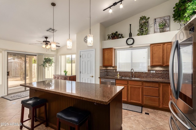 11318 S Hopi Dr, Goodyear, AZ 85338 - kitchen with stainless steel appliances, a sink, brown cabinetry, a breakfast bar area, and ceiling fan
