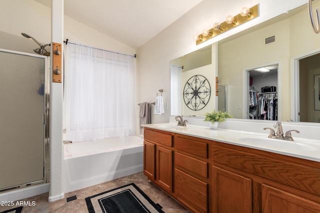 11318 S Hopi Dr, Goodyear, AZ 85338 - bathroom featuring lofted ceiling, a shower stall, a garden tub, double vanity, and a walk in closet