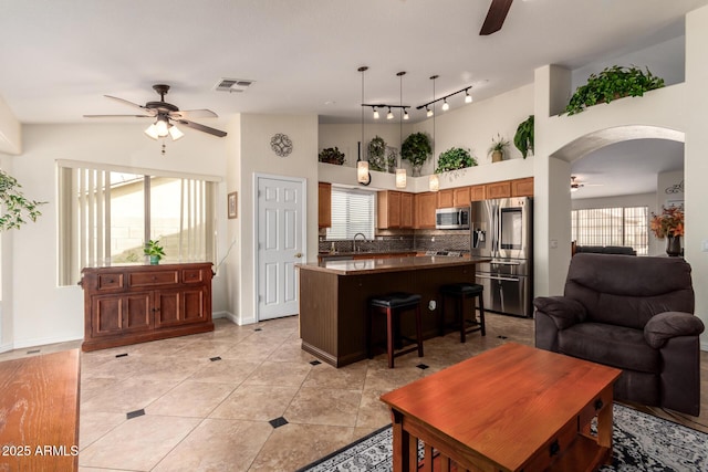 11318 S Hopi Dr, Goodyear, AZ 85338 - living area with ceiling fan, arched walkways, baseboards, a high ceiling, and rail lighting
