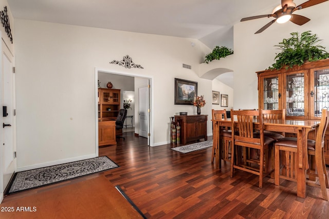 11318 S Hopi Dr, Goodyear, AZ 85338 - dining space featuring arched walkways, ceiling fan, dark wood-style floors, baseboards, and high vaulted ceiling