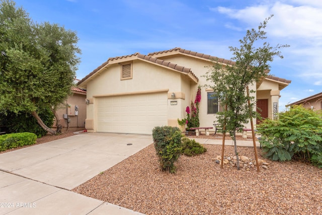 mediterranean / spanish-style home with stucco siding, a garage, driveway, and a tiled roof