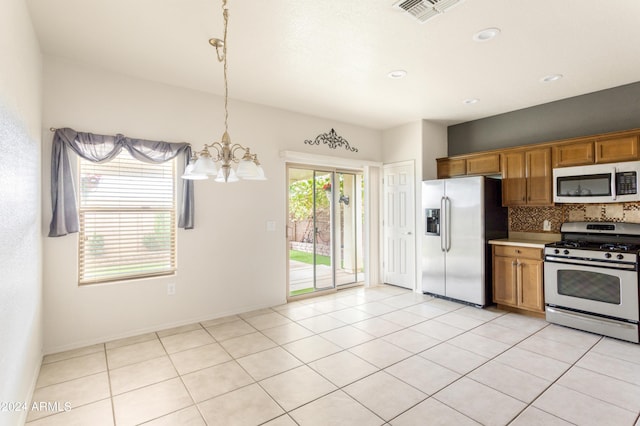 kitchen featuring visible vents, backsplash, pendant lighting, brown cabinets, and appliances with stainless steel finishes