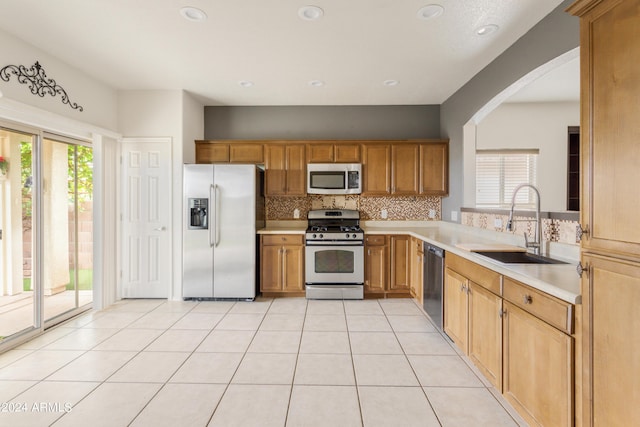 kitchen featuring light tile patterned floors, a sink, decorative backsplash, light countertops, and appliances with stainless steel finishes