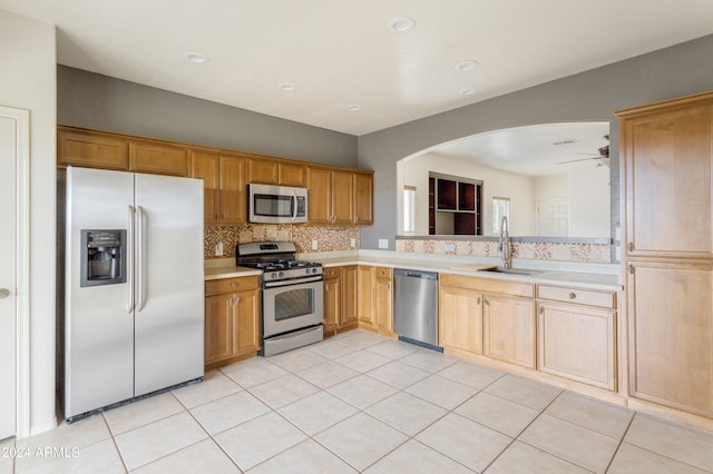 kitchen featuring appliances with stainless steel finishes, sink, light tile patterned flooring, ceiling fan, and tasteful backsplash