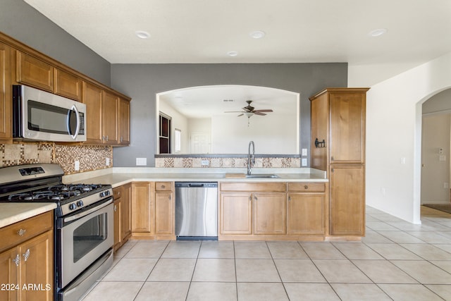 kitchen featuring stainless steel appliances, sink, decorative backsplash, ceiling fan, and light tile patterned flooring