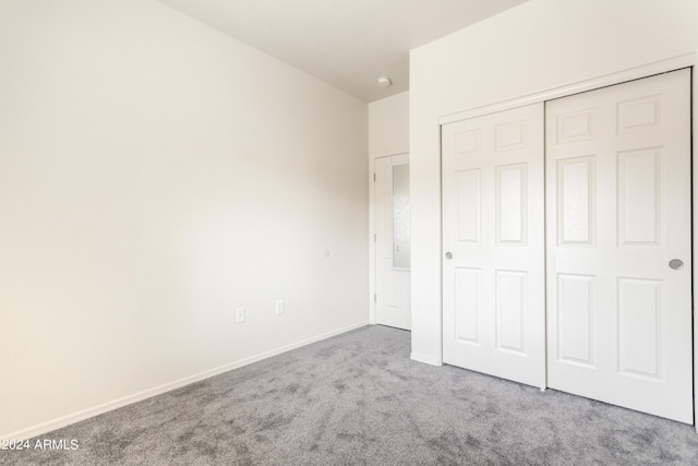 unfurnished bedroom with carpet, a closet, and baseboards