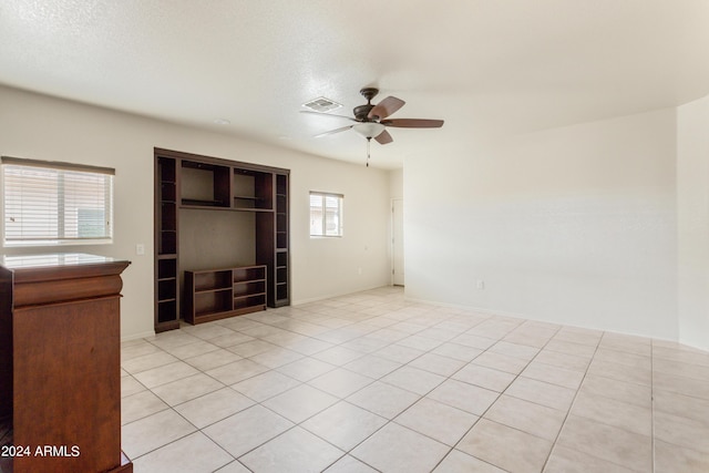 empty room featuring light tile patterned floors, a ceiling fan, visible vents, and a textured ceiling