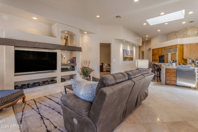 tiled living room with a skylight, a high ceiling, and built in shelves