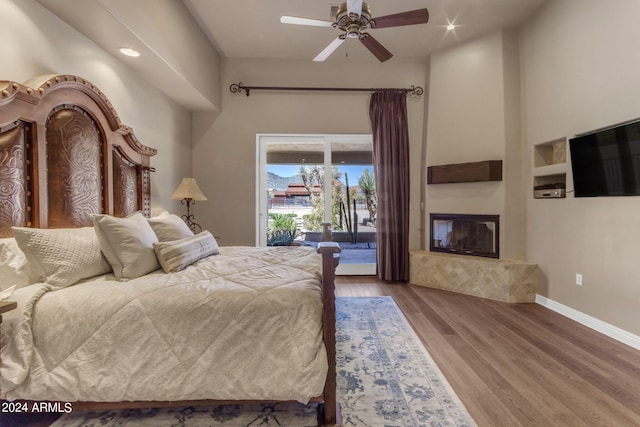 bedroom featuring ceiling fan, a tile fireplace, access to outside, and dark wood-type flooring