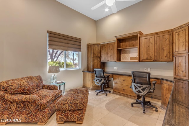 tiled office space featuring built in desk, ceiling fan, and a high ceiling