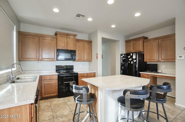 kitchen with a breakfast bar, built in desk, sink, a center island, and black appliances