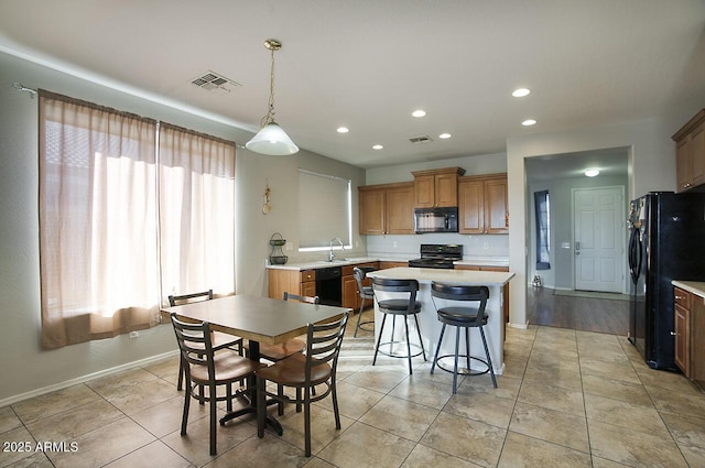 kitchen with pendant lighting, sink, a center island, black appliances, and light tile patterned flooring