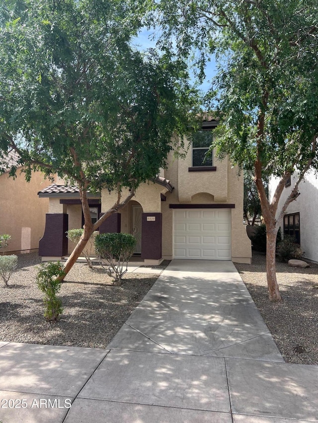 view of property hidden behind natural elements with stucco siding, a garage, and driveway