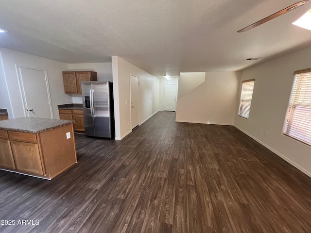 unfurnished living room with dark wood-type flooring, baseboards, and a ceiling fan