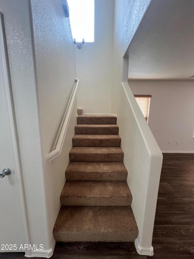 staircase with wood finished floors and healthy amount of natural light