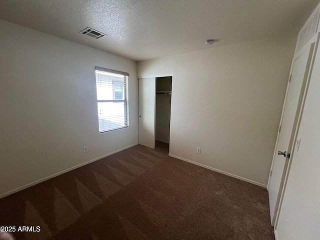 unfurnished bedroom with carpet, a closet, baseboards, and a textured ceiling