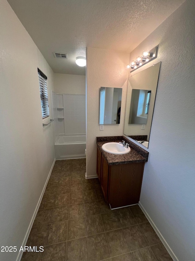 full bath featuring a textured ceiling, vanity, tile patterned flooring,  shower combination, and baseboards