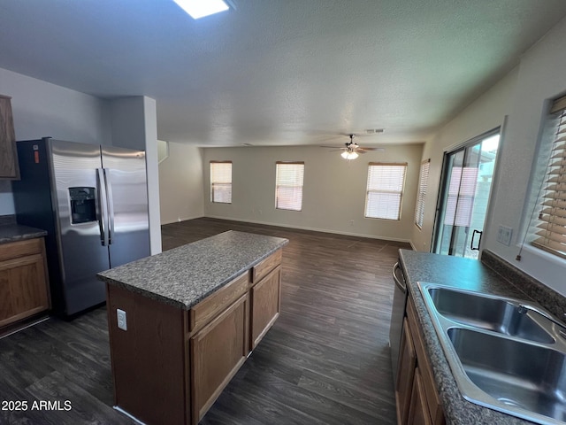 kitchen with stainless steel fridge, a sink, dark countertops, and dark wood-type flooring