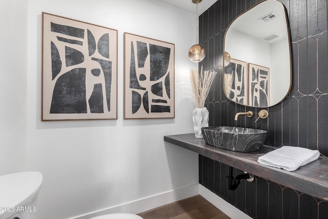 bathroom with toilet, hardwood / wood-style floors, and sink