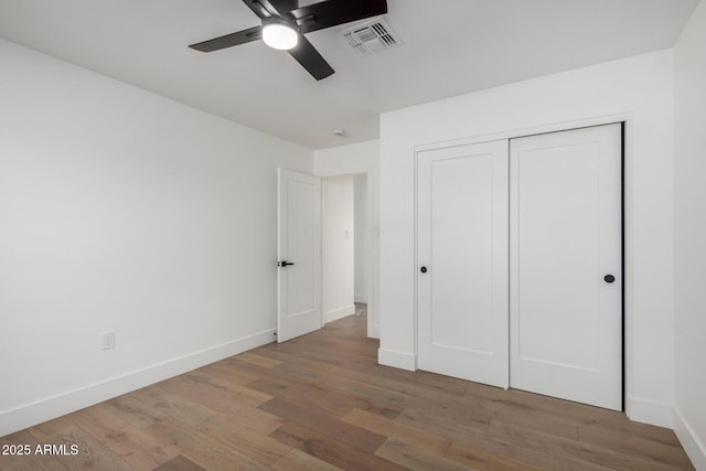 unfurnished bedroom with ceiling fan, a closet, and hardwood / wood-style flooring