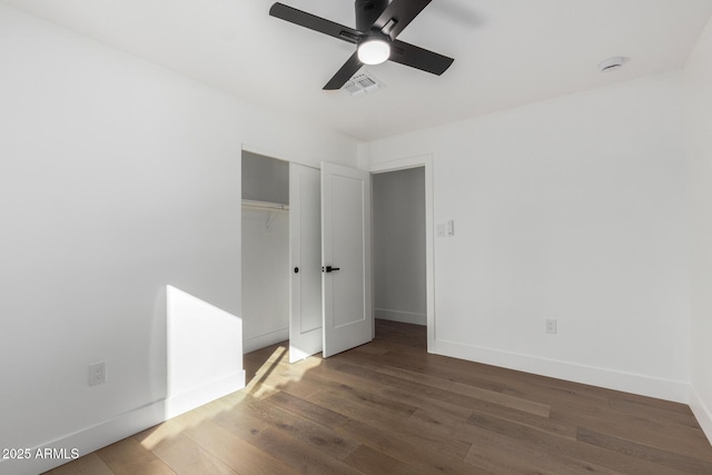 unfurnished bedroom with ceiling fan, dark hardwood / wood-style flooring, and a closet