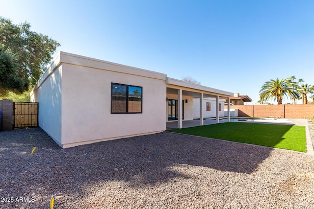 back of property with a lawn and a patio