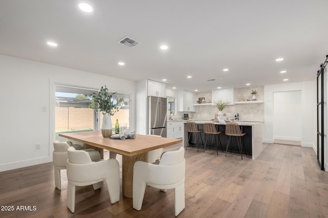 dining area featuring light wood-type flooring and a barn door