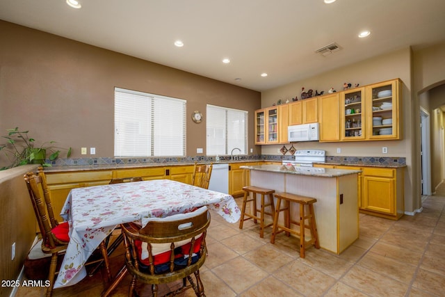 10242 E Pantera Ave, Mesa, AZ 85212 - kitchen with white appliances, a center island, recessed lighting, glass insert cabinets, and a breakfast bar