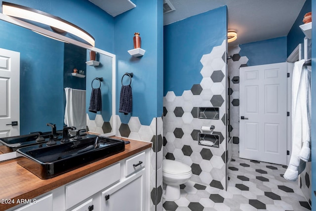 bathroom featuring a shower with door, vanity, and toilet