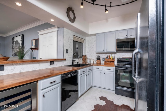 kitchen featuring butcher block countertops, beverage cooler, sink, and black appliances